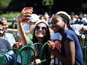 US player Cori Gauff (R) poses for a selfie with fans after a session on the practice courts at The All England Tennis Club in Wimbledon, southwest London, on July 4, 2019, on the fourth day of the 2019 Wimbledon Championships tennis tournament. - Coco Gauff, the 15-year-old schoolgirl who stunned five-time champion Venus Williams in the first round, continued her Wimbledon dream debut on Wednesday when she eased into the last 32 and claimed: "I can beat anyone." Next up for Gauff is a last 32 clash against world number 60 Polona Hercog of Slovenia on July 5.