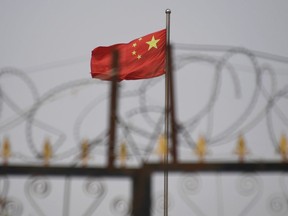 This photo taken on June 4, 2019 shows the Chinese flag behind razor wire at a housing compound in Yangisar, south of Kashgar, in China's western Xinjiang region.