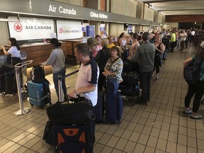 Passengers from an Australia-bound Air Canada flight diverted to Honolulu Thursday, July 11, 2019, after about 35 people were injured during turbulence, stand in line at the Air Canada counter at Daniel K. Inouye International Airport to rebook flights. Air Canada said the flight from Vancouver to Sydney encountered "un-forecasted and sudden turbulence," about two hours past Hawaii when the plane diverted to Honolulu.
