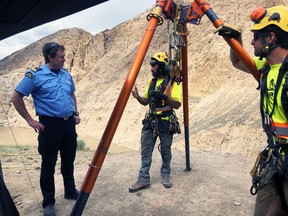 A federal Fisheries officer talks to rock scalers setting up to be lowered over the cliff.