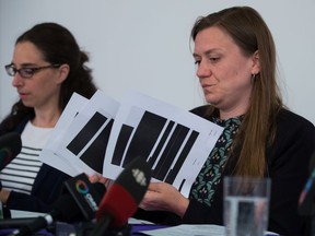 Meghan McDermott, front right, a lawyer with the B.C Civil Liberties Association, holds a few redacted pages from the thousands disclosed by the Canadian Security Intelligence Service, while speaking as Alexandra Woodsworth, back, Campaigns Manager for Dogwood B.C., listens during a news conference in Vancouver, on Monday July 8, 2019. The BCCLA alleges that CSIS was monitoring the organizing activities and peaceful protests of Indigenous groups and environmentalists who were opposed to the now-defunct Enbridge Northern Gateway Pipeline project.