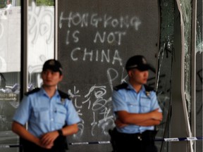 Policemen stand in front of graffiti on the walls of the Legislative Council, a day after protesters broke into the building in Hong Kong, China July 2, 2019.  REUTERS/Jorge Silva