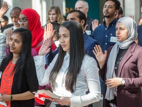 New Canadians, including Raisa Punzalan, (C), swear allegiance as the Institute for Canadian Citizenship, together with Immigration, Refugees and Citizenship Canada, and the National Gallery of Canada, held a special community citizenship ceremony in the Great Hall at the National Gallery of Canada.