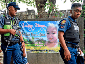Policemen walk past a banner during the wake for three-year-old Kateleen Myca Ulpina, killed during a sting operation conducted by the police, in Rodriguez, east of Manila on July 7, 2019.