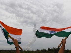Indian residents wave Indian national flags as The Indian Space Research Organisation's (ISRO) Chandrayaan-2 (Moon Chariot 2), on board the Geosynchronous Satellite Launch Vehicle (GSLV-mark III-M1), launches in Sriharikota in the state of Andhra Pradesh on July 22, 2019.