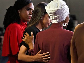 Representative Ayanna Pressley looks on as Ilhan Omar holds the shoulder of Alexandria Ocasio-Cortez during a news conference, to address remarks by US President Donald Trump earlier in the day, at the US Capitol in Washington, DC on July 15, 2019.