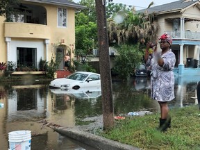 A woman stands photographing the scene in a flooded street in New Orleans, Louisiana, U.S., July 10, 2019.