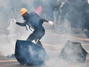 A protester throws back a round of tear gas fired at protesters by the police during a demonstration in the district of Yuen Long in Hong Kong on July 27, 2019.