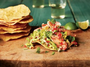 Tostada shells are slathered with guacamole and topped with shredded lettuce and Dungeness crabmeat yielding four appetizer servings from a mere 1/2 pound of crab. Photo: Sara Remington