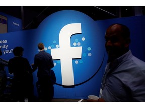 Attendees walk past a Facebook logo during Facebook Inc's F8 developers conference in San Jose, California, U.S., April 30, 2019.