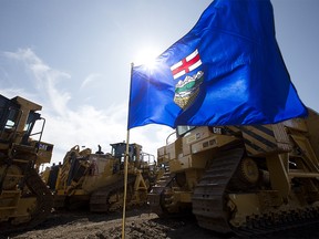 An Alberta provincial flag is surrounded by pipeline heavy machinery following a press conference at SA Energy Group, in Edmonton Wednesday Aug. 21, 2019. It was announced that construction on the Trans Mountain Pipeline will restart within the month. Contractors, like SA Energy Group, now have 30 days to hire crews, get equipment in place, and develop detailed construction plans. Photo by David Bloom
