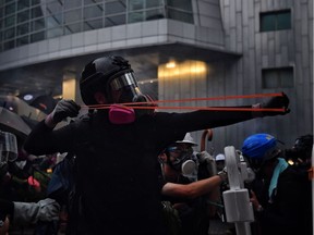 A protester uses a slingshot against the police in Hong Kong on August 25, 2019 in the latest opposition to a planned extradition law that has since morphed into a wider call for democratic rights in the semi-autonomous city. - Protesters gathered at a sports stadium as Hong Kong braced for more anti-government rallies, a day after clashes returned to the city's streets following several days of relative calm. Photo: Lillian Suwanrumpha/AFP