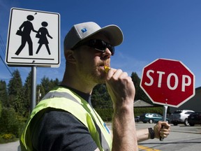 Christian Behnke, a crossing guard at Ecole Cleveland Elementary, is prepared for traffic congestion at the start of the school year. Photo: Gerry Kahrmann/Postmedia