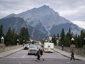 Pedestrians cross the street in Banff, Alta., in Banff National Park on July 21, 2017. A campground in Banff National Park where a wolf attacked a man in a tent last week has reopened to the public.THE CANADIAN PRESS/Jeff McIntosh