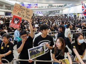 Protesters hold up placards for arriving travellers at the arrivals hall of Hong Kong International Airport.