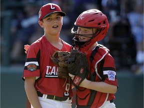 Canada's starting pitcher Timmy Piasentin (9) gets a hug from catcher Everett Bertsch as they wait for manager Bruce Darwart during a pitching change in the fifth inning of an elimination baseball game against Curacao at the Little League World Series tournament in South Williamsport, Pa., Monday, Aug. 19, 2019.