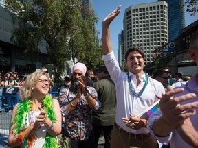 Prime Minister Justin Trudeau waves while marching in the Vancouver Pride Parade with Green party leader Elizabeth May and the NDP's Jagmeet Singh.