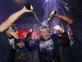 Masahiro Tanaka of the New York Yankees is doused with champagne by teammates Austin Romine, left, and Cameron Maybin after the Yanks clinched the American League East division title on Sept. 19, 2019 in the Bronx.