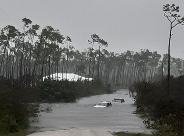 Rising waters cover cars on a road in Freeport in the Grand Bahamas on September 3, 2019, as hurricane Dorian passes. - Hurricane Dorian weakened slightly as it crawled towards the southeast coast of the United States on Tuesday after leaving at least five people dead and a swathe of destruction in the Bahamas.
