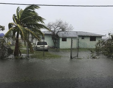 A car is parked near a flooded house in Freeport in the Grand Bahamas on September 3, 2019, as hurricane Dorian passes. - Hurricane Dorian weakened slightly as it crawled towards the southeast coast of the United States on Tuesday after leaving at least five people dead and a swathe of destruction in the Bahamas.