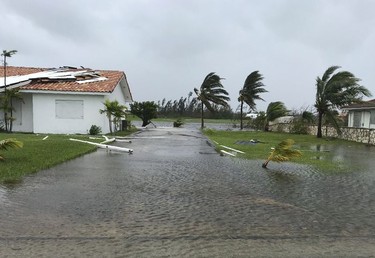 Debris is scattered on a flooded road near houses in Freeport in the Grand Bahamas on September 3, 2019, as hurricane Dorian passes. - Hurricane Dorian weakened slightly as it crawled towards the southeast coast of the United States on Tuesday after leaving at least five people dead and a swathe of destruction in the Bahamas.
