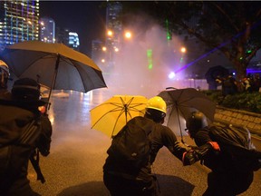 Protesters protect themselves after police fired water cannon toward them after the group occupied a main road in the Admiralty area in Hong Kong on September 28, 2019, on the fifth anniversary of the "Umbrella Movement". - Thousands of Hong Kongers gathered on September 28 to mark the fifth anniversary of the 'Umbrella Movement', the failed pro-democracy campaign that laid the groundwork for the massive protests currently engulfing the city.