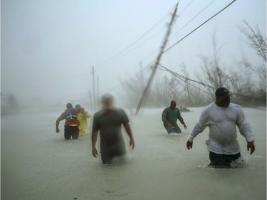 Volunteers walk under the wind and rain from Hurricane Dorian through a flooded road as they work to rescue families near the Causarina bridge in Freeport, Grand Bahama, Bahamas, Tuesday, Sept. 3, 2019. The storm's punishing winds and muddy brown floodwaters devastated thousands of homes, crippled hospitals and trapped people in attics.