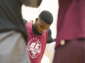 Bahamian Joshua Dames, 18, from Freeport, bows his head during a team prayer before basketball practice at Burnaby B.C. Christian Prep.