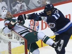 Winnipeg Jets defenceman Dustin Byfuglien (right) pushes Minnesota Wild forward Jason Zucker into the net in Winnipeg on Wed., April 11, 2018. (Kevin King /Postmedia Network)