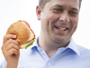 This is an edited photo illustration of Andrew Scheer holding a burger.