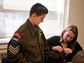 Grade 7 student Tristan Levesque tries on a Second World War era battle dress jacket as classmate Olivia Puff looks on at their middle school in Saint John, N.B. The clothing is one of several items in a kit provided free of charge to schools by the Canadian War Museum focusing on Canada's role in the Second World War. THE CANADIAN PRESS/HO-Canadian War Museum MANDATORY CREDIT