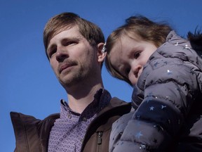 Edouard Maurice, centre, speaks to reporters outside court while holding his daughter Teal in Okotoks, Alta., Friday, March 9, 2018. A southern Alberta man who had charges dropped against him last year after firing shots at suspected thieves on his rural property is being sued by a man who was wounded in the incident.