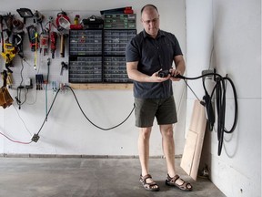 In this Wednesday May 23, 2018, photo, Gregory Burnett holds the charger to his 2018 Nissan Leaf plugin electric car in his garage.