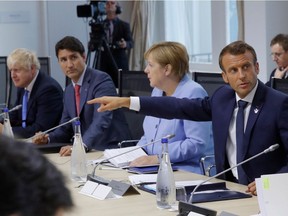 French President Emmanuel Macron (pointing), German Chancellor Angela Merkel, Prime Minister Justin Trudeau and Britain's Prime Minister Boris Johnson attend a working lunch during the G7 summit in Biarritz, France, in August. Globally, threats are rising against western democracies. But Trudeau sees no need to join a leaders' debate on the issue.