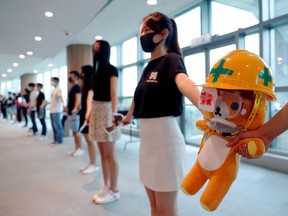 Medical students hold a stuffed doll with its eye covered as they form a human chain during a protest against police brutality at the faculty of medicine in The University of Hong Kong.