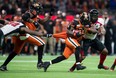 B.C. Lions' Brandon Rutley, front run, carries the ball in front of Ottawa Redblacks' Jeff Knox Jr., back right, as Avery Ellis, left, pulls on his jersey in Vancouver on Friday.