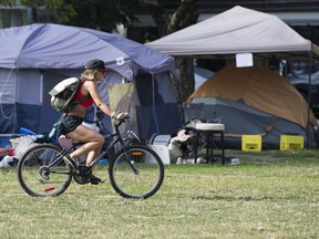 A cyclist rides through open space, and near tents, in East Vancouver's Oppenheimer Park in early September.