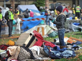 FILE - Oct. 16, 2014. A woman sorts through her belongings as tents come down and police and city workers clean up Oppenheimer Park   in   Vancouver  on October 16, 2014.