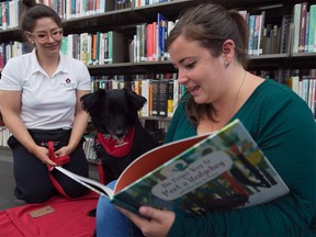 Anna Boekoven, right, and Ashten Black, from Saint John Ambulance therapy dogs, read to a dog named "Pig" at the Vancouver Public Library in downtown Vancouver, Friday, Sept. 13, 2019.