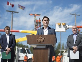 Minister of Fisheries, Oceans and the Canadian Coast Guard, Jonathan Wilkinson, left, and B.C. Premier John Horgan, right, look on as Prime Minister Justin Trudeau makes an announcement at B.C. Hydro Trades Training Centre in Surrey on Aug. 29, 2019.