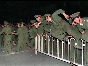People Liberation Army (PLA) soldiers leap over a barrier on Tiananmen Square in central Beijing on June 4, 1989 during heavy clashes with people and dissident students. On the night of June 3 and 4, 1989, Tiananmen Square sheltered the last pro-democracy supporters. Chinese troops forcibly marched on the square to end a weeks-long occupation by student protestors, using lethal force to remove opposition it encountered along the way. Hundreds of demonstrators were killed in the crackdown as tanks rolled into the environs of the square. Photo: Catherine Henriette/AFP/Getty Images
