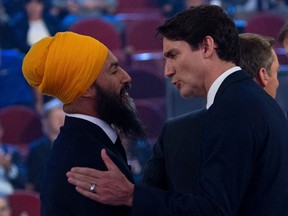 Canada's Prime Minister and Liberal leader Justin Trudeau (C) and NDP leader Jagmeet Singh shake hands following the Federal leaders French language debate at the Canadian Museum of History in Gatineau, Quebec on October 10, 2019. (Photo by Adrian Wyld / POOL / AFP)