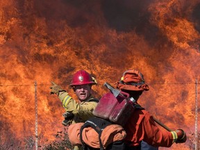 Firefighters prepare to put out flames on the road leading to the Reagan Library during the Easy Fire in Simi Valley, California on October 30, 2019.