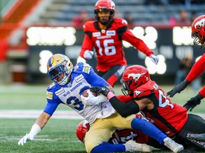 Winnipeg Blue Bombers Andrew Harris, left, runs the ball against the Calgary Stampeders during their game in Calgary, Oct. 19, 2019. (Al Charest/Postmedia Network)