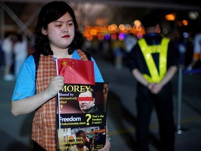 A woman holds signs against Houston Rockets general manager Daryl Morey and Hong Kong protests outside the Mercedes-Benz Arena before the NBA exhibition game between Brooklyn Nets and Los Angeles Lakers in Shanghai, China on Oct. 10.