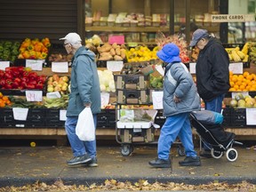 People walk past one of dozens of family-run groceries on Fraser Street in Vancouver South, the most diverse riding in B.C.