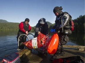 Diver Karen Wille (left) and a passer-by help diver Dennis Chow bring up bags of trash from beneath the floating footbridge on Sasamat Lake in Port Moody. The volunteer divers are part of Divers for Cleaner Lakes and Oceans and perform clean-up dives on a regular basis at several B.C. lakes.