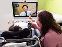 11 year old Caitlyn, with the help of mom Amanda Sidhu, gives Dr.  James Lee waves during an online meeting with a specialist at Children's Hospital of British Columbia.  Caitlin was in Abbotsford, Lee was in Vancouver.
