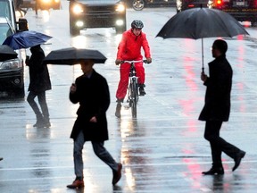 Pedestrians brave the rain as Environment Canada issues a heavy rain and wind weather alert.