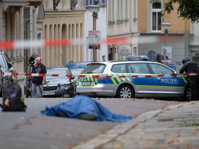 A body laying in the street is covered as police block the area around the site of a shooting in Halle an der Saale, eastern Germany, on October 9, 2019.